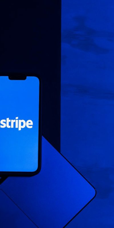 Photo by Julio Lopez A smartphone displaying the Stripe app placed on a laptop keyboard with a blue monochromatic tone.