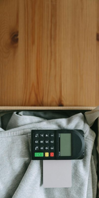Close-up of a card payment terminal on top of gray clothing in a wooden box, indoors.