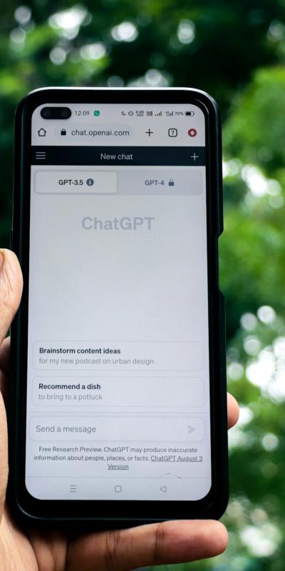 Close-up of a hand holding a smartphone displaying ChatGPT outdoors.