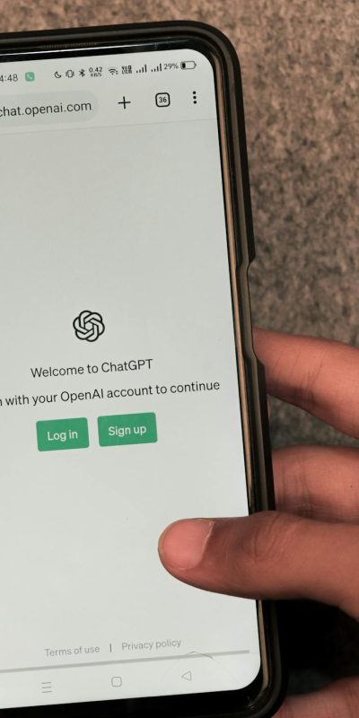 Close-up of hands using smartphone with ChatGPT app open on screen.