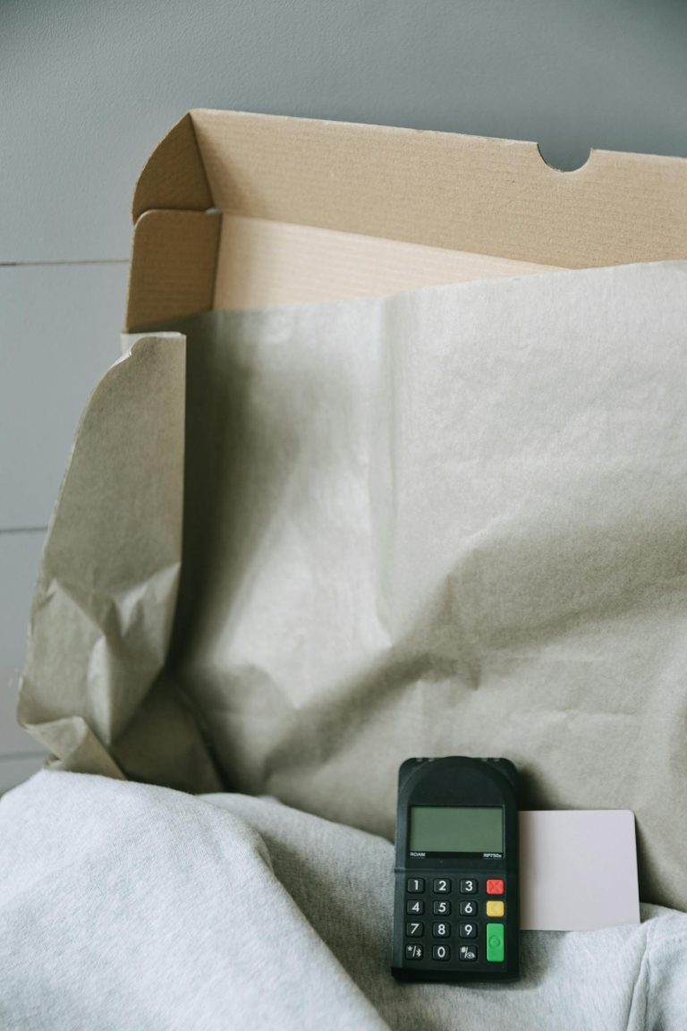 Image of a payment terminal with a cardboard box and paper, representing online shopping and contactless payment.